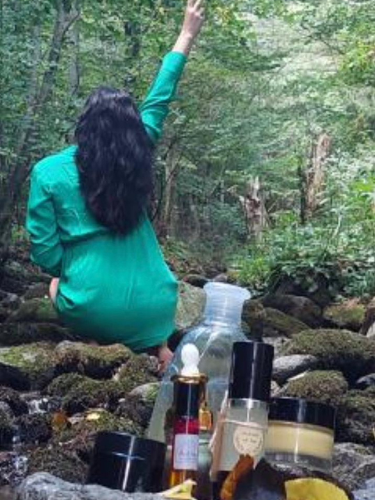 brm. produkty v lese na skale so ženou otočenou chrbtom v zelených šatách.